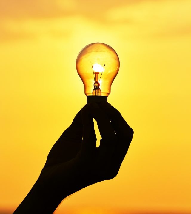 Silhouette of a light bulb at sunset.